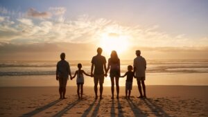 A family of 6 holding hands watching the sun set by the beach