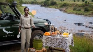 Female Kenyan ranger flipping pancakes at a breakfast stop overlooking the Mara River