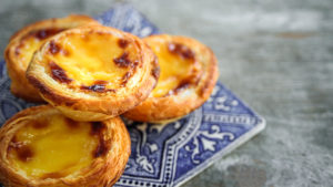 Portuguese pastel de nata custard pastries on an iconic blue and white azulejo tile