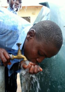 child drinking water from a tap